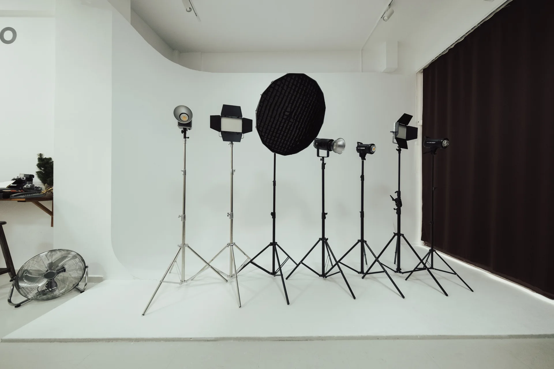 Beyaz sonsuz fon üzerinde sıralanmış softbox, panel ışıklar ve ışık ayakları.